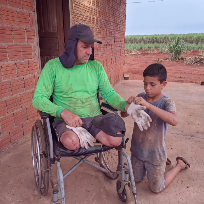 Valdir recebendo as luvas de trabalho das mãos de um menino, em frente de casa